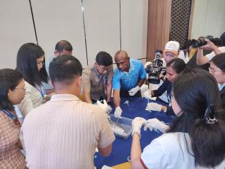 a group of fisheries officers around a table participating in a training course in monitoring, control and surveillance